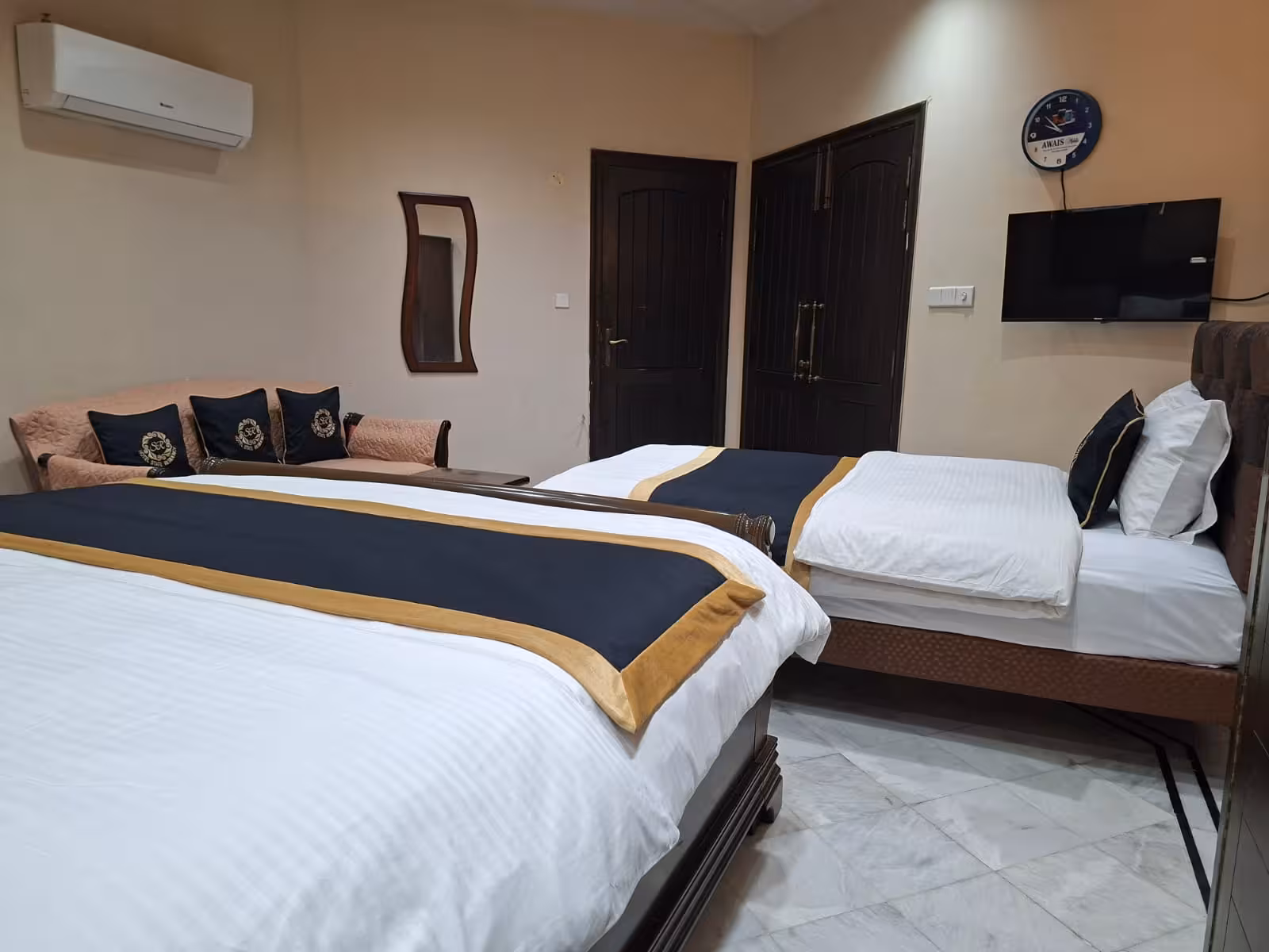 Twin bed family room with wall-mounted TV and wooden decor - Hotel State Residency Bahawalpur